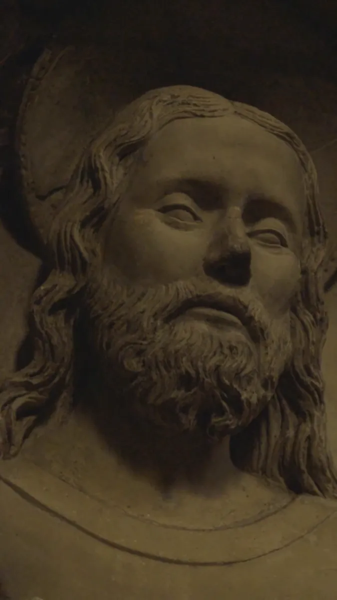 Gros plan sur le visage d'une statue ancienne en pierre, lumière chaude