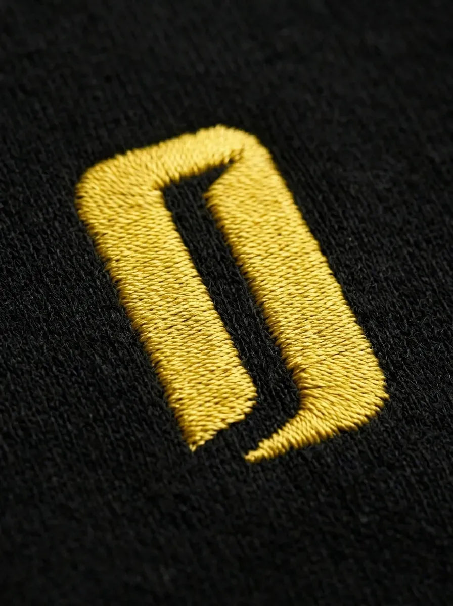 Plan macro IA sur une broderie jaune en relief sur un sweat noir