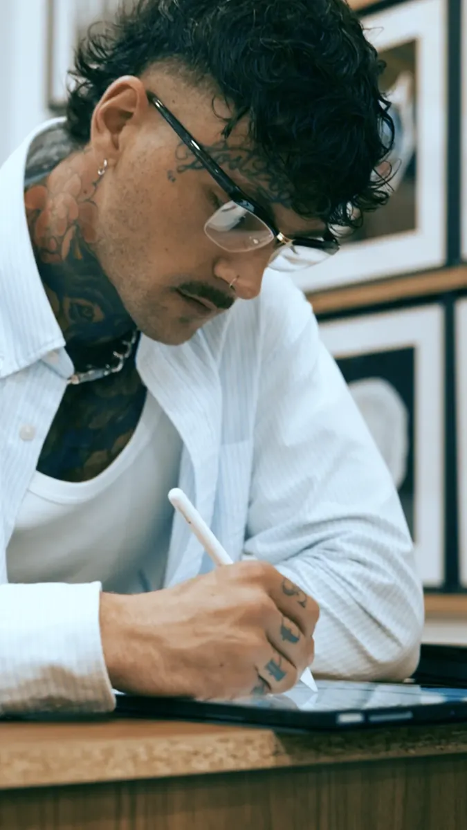 Tatoueur en train de dessiner à son bureau, tournage en salon de tatouage