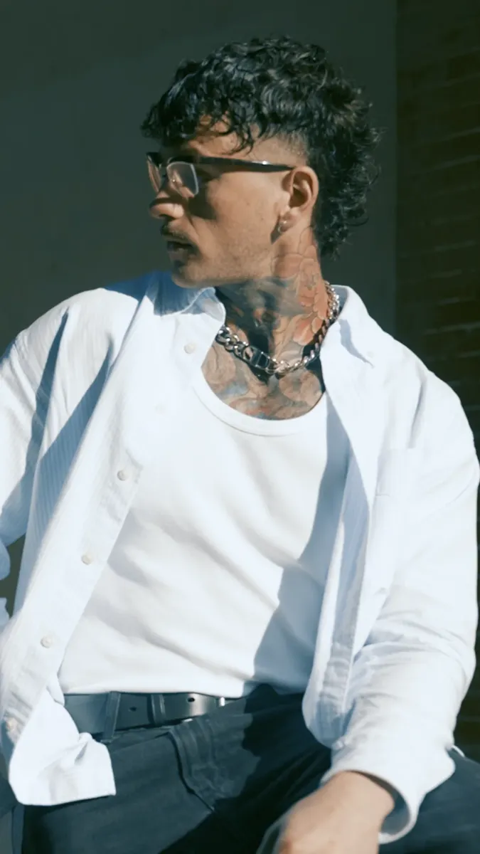 Portrait d'un tatoueur en chemise blanche, assis, lumière naturelle